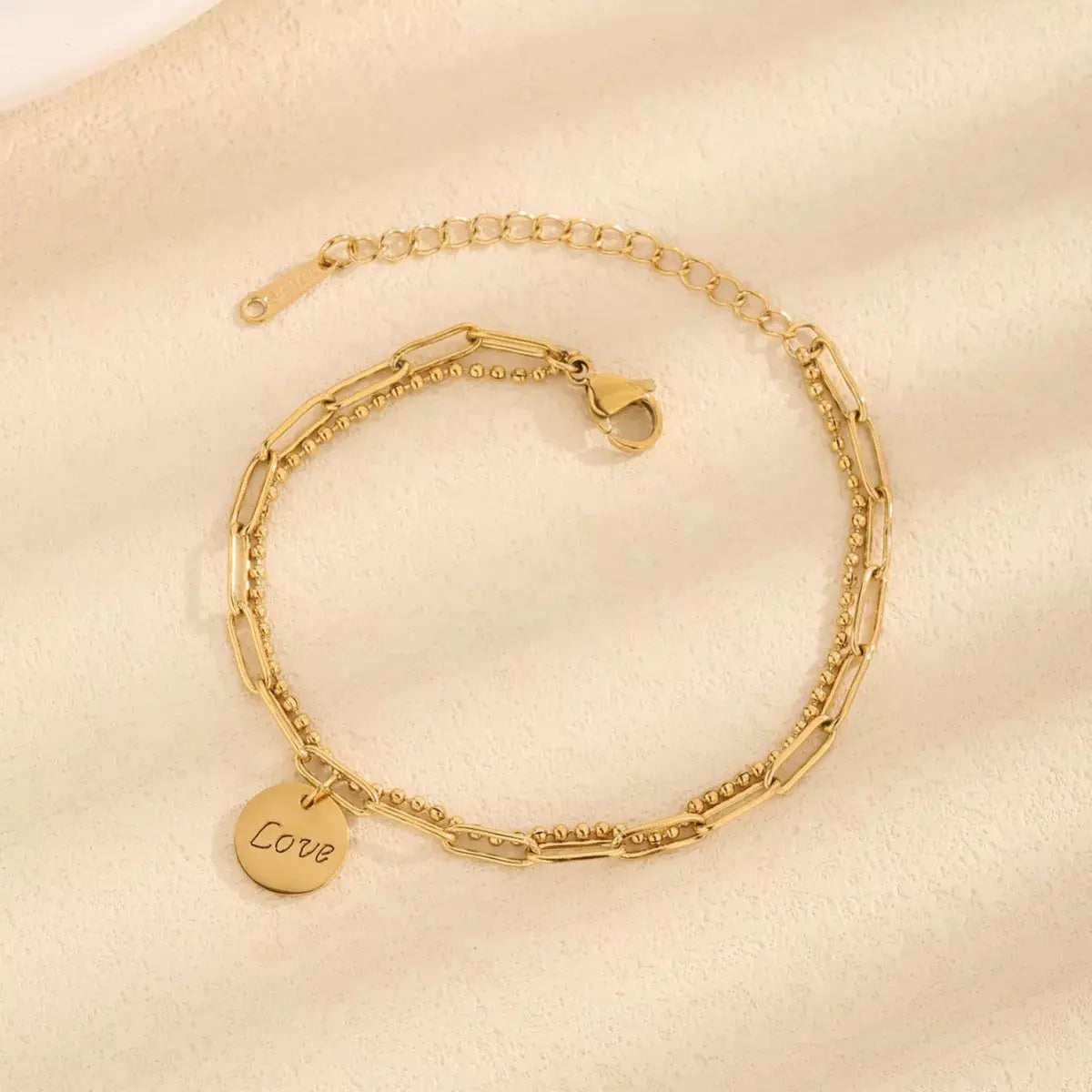 Close-up of LOVE letter charm on gold bracelet