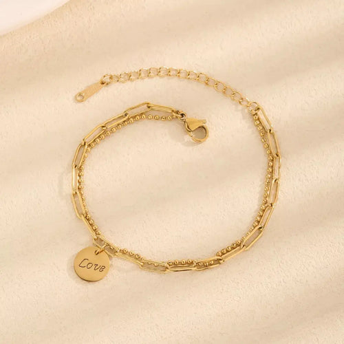 Close-up of LOVE letter charm on gold bracelet