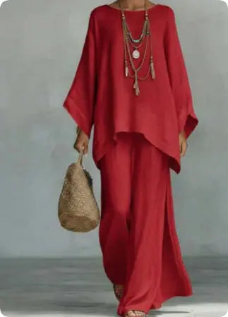 Person wearing a red outfit with a textured necklace against a plain background