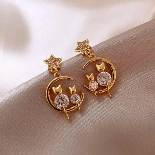 Close-up of rhinestone and cat's eye stone on gold dangle earrings