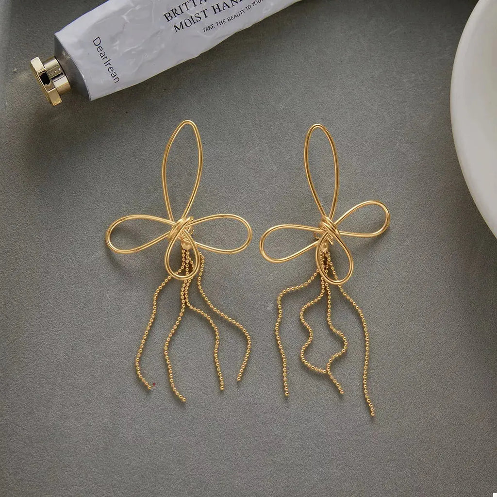 Close-up of tassel bow detail on gold earrings