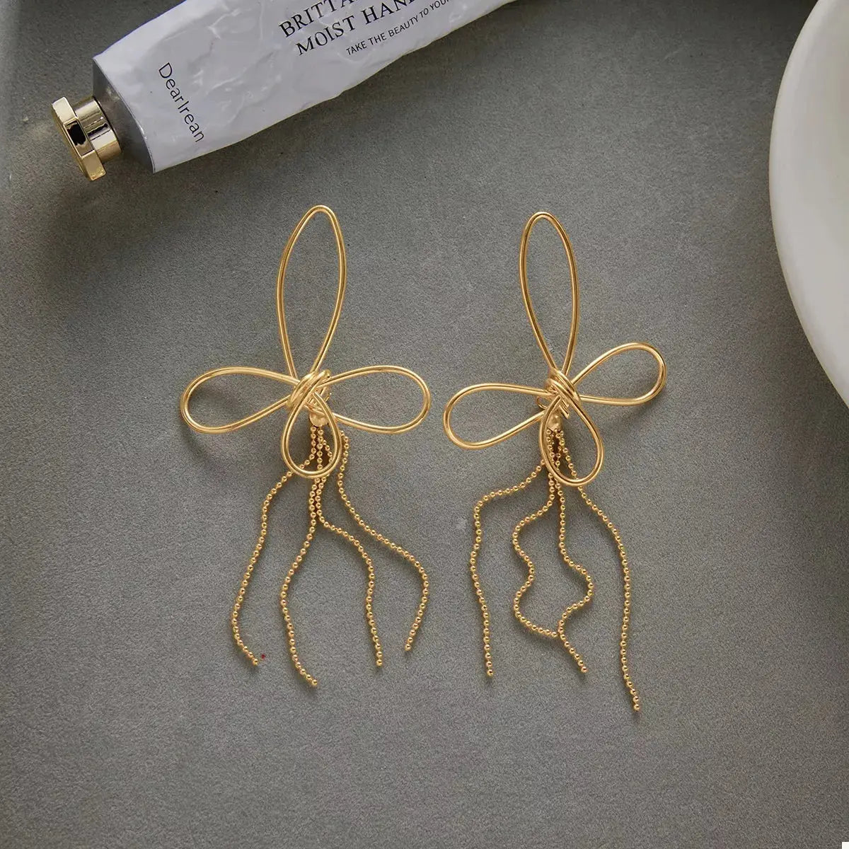Close-up of tassel bow detail on gold earrings