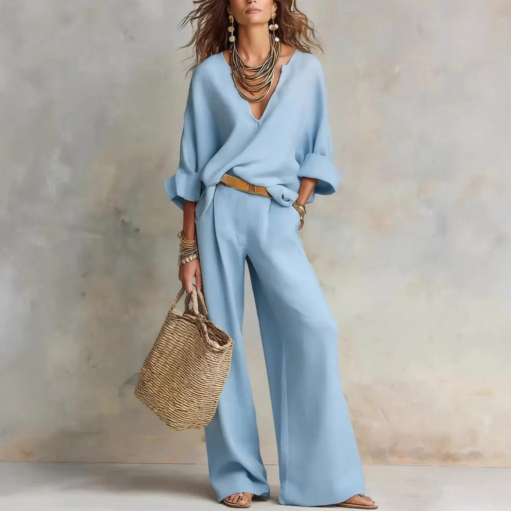 Woman wearing a light blue outfit holding a straw bag against a neutral background