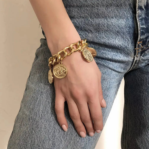 Close-up of coin charm on gold bracelet