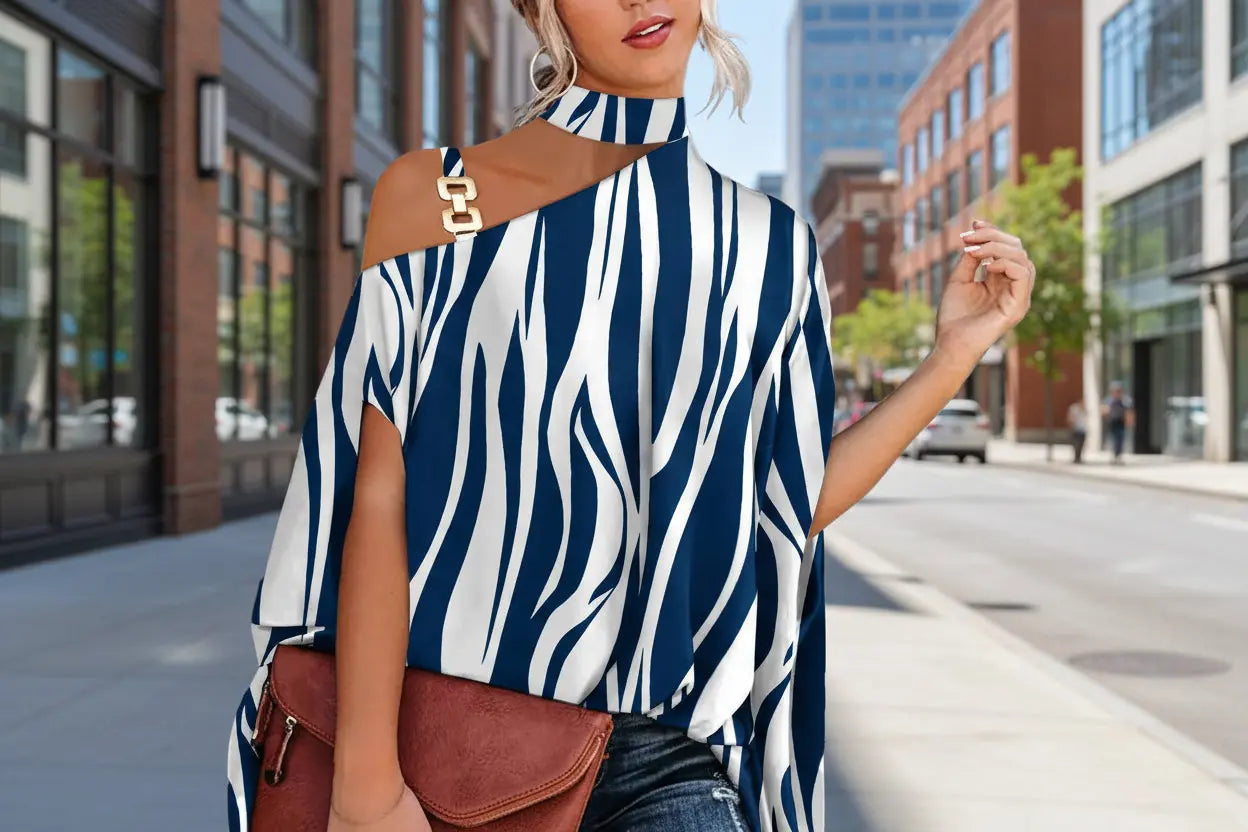 Woman wearing a blue and white patterned top with a brown bag on a city street.