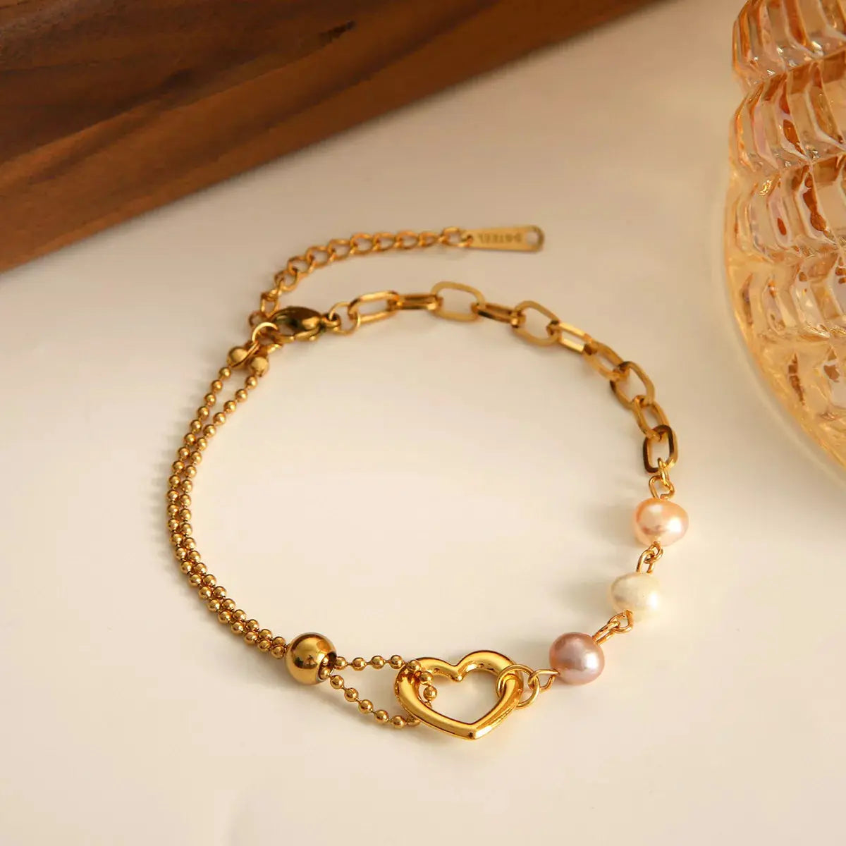 Close-up of pearl and heart detail on gold bracelet