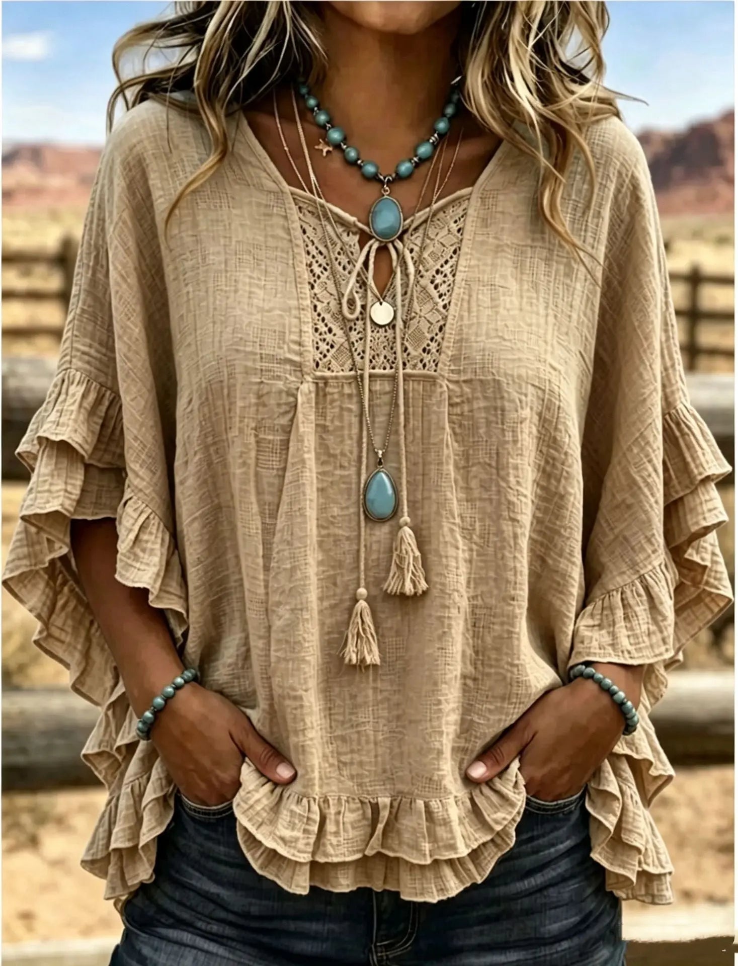 Beige blouse with ruffled sleeves and lace details, worn with a necklace, against a blurred outdoor background.