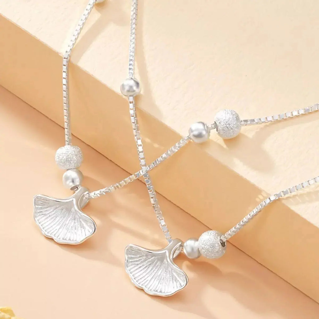Close-up of ginkgo leaf charm on layered bracelet