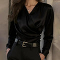 Person wearing a black long-sleeve top with a belt against a neutral background