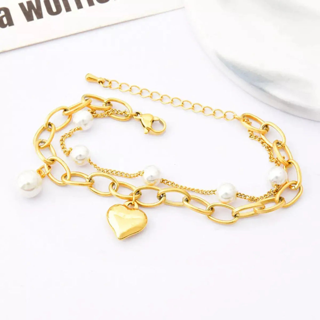 Close-up of pearl and heart charm on gold bracelet