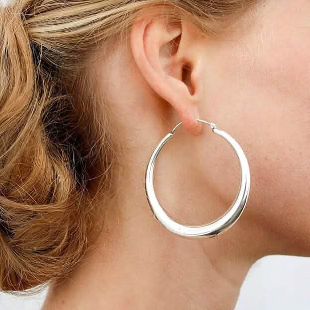 Silver hoop earring worn by a person with blonde hair.