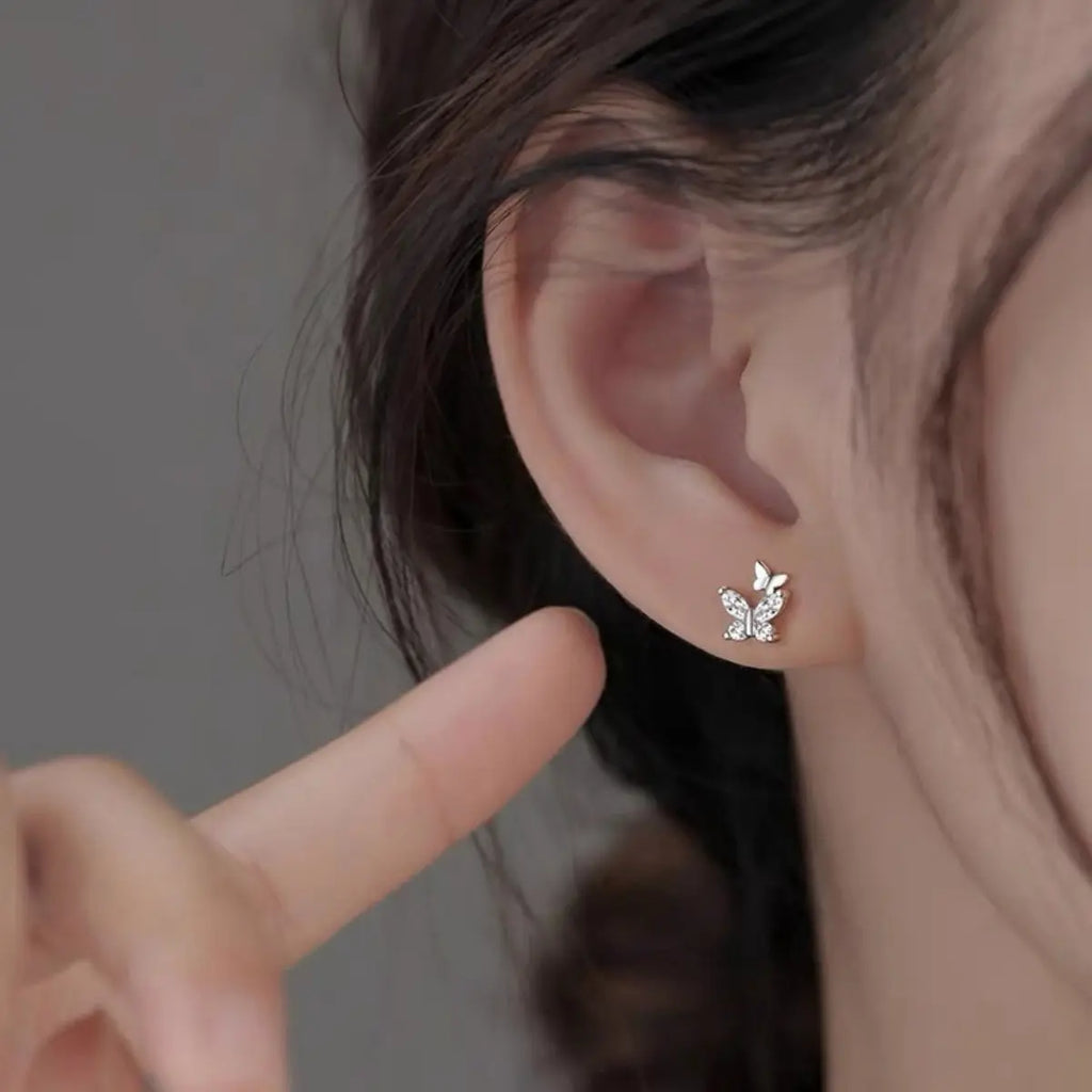 Woman wearing silver butterfly stud earrings