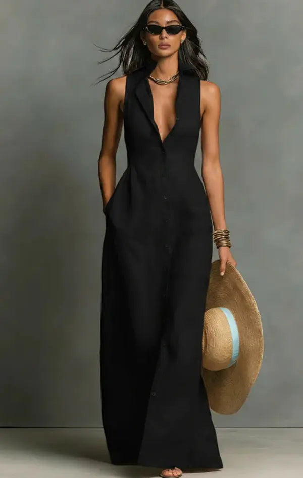 Woman wearing a black sleeveless jumpsuit holding a straw hat against a gray background