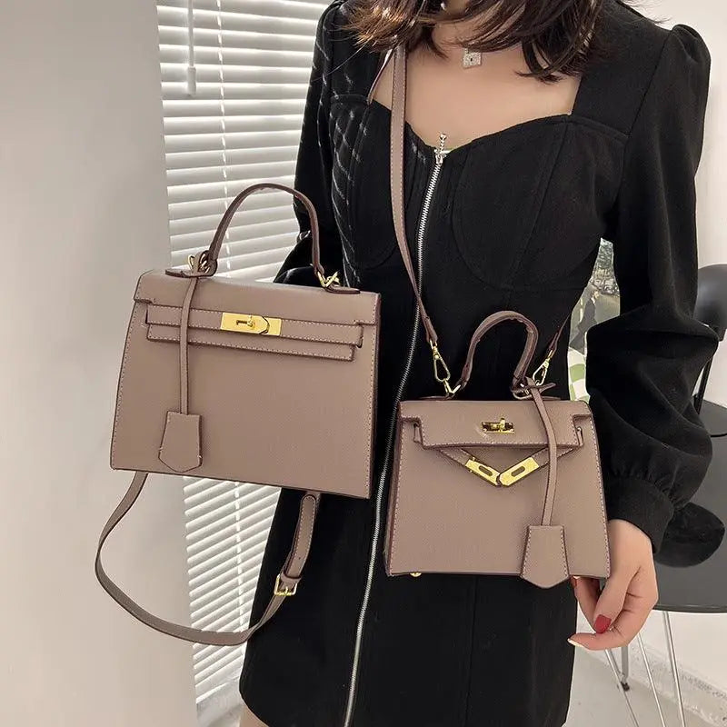 Person holding two beige handbags with gold hardware in an indoor setting.