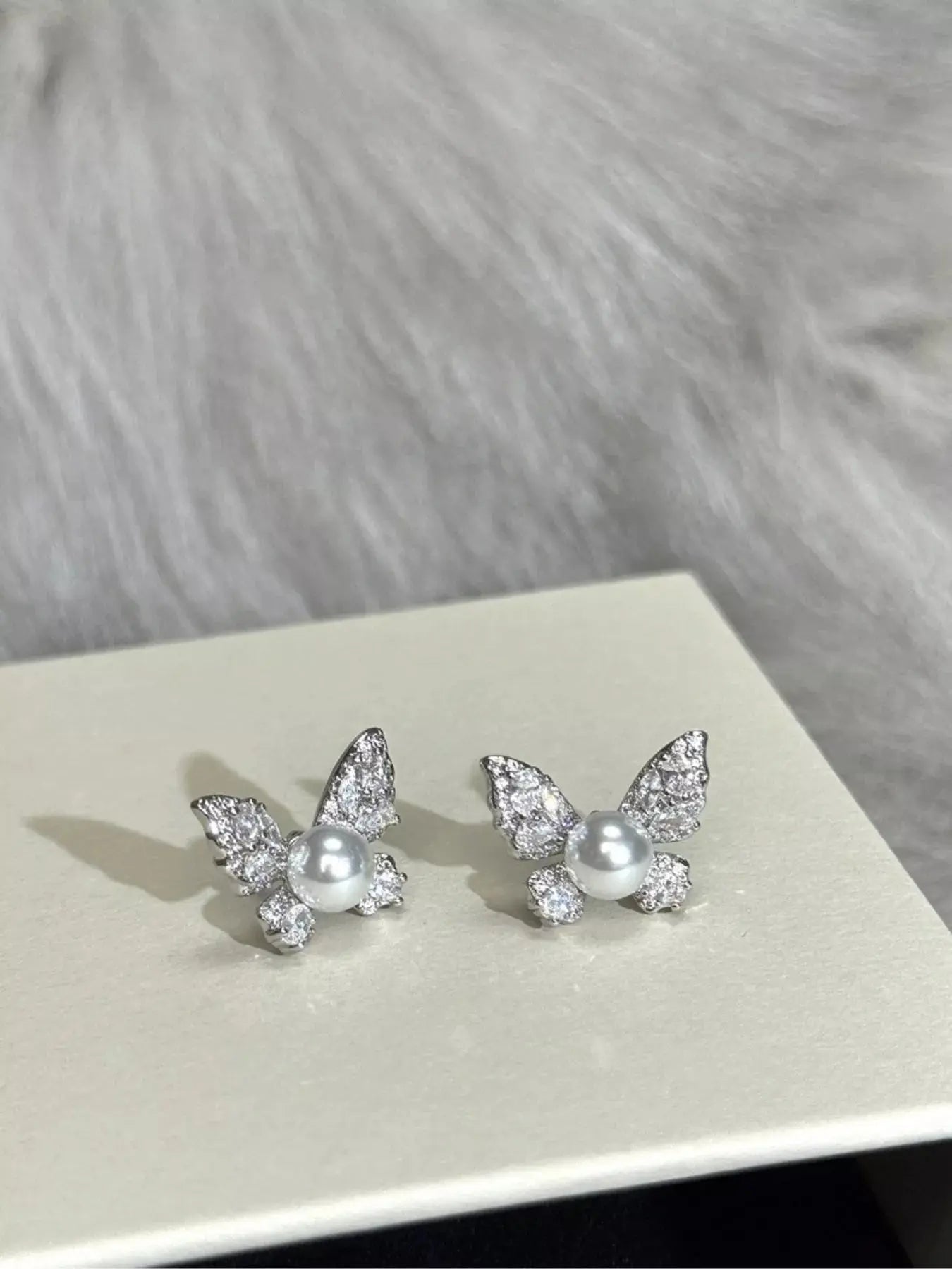 Butterfly pearl stud earrings from Vicsxox on display