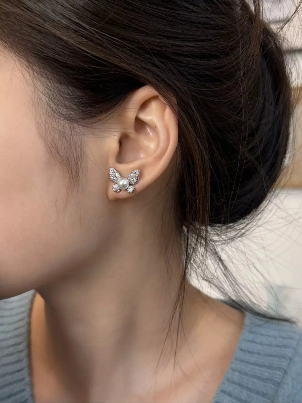 Close-up of butterfly design on pearl stud earrings
