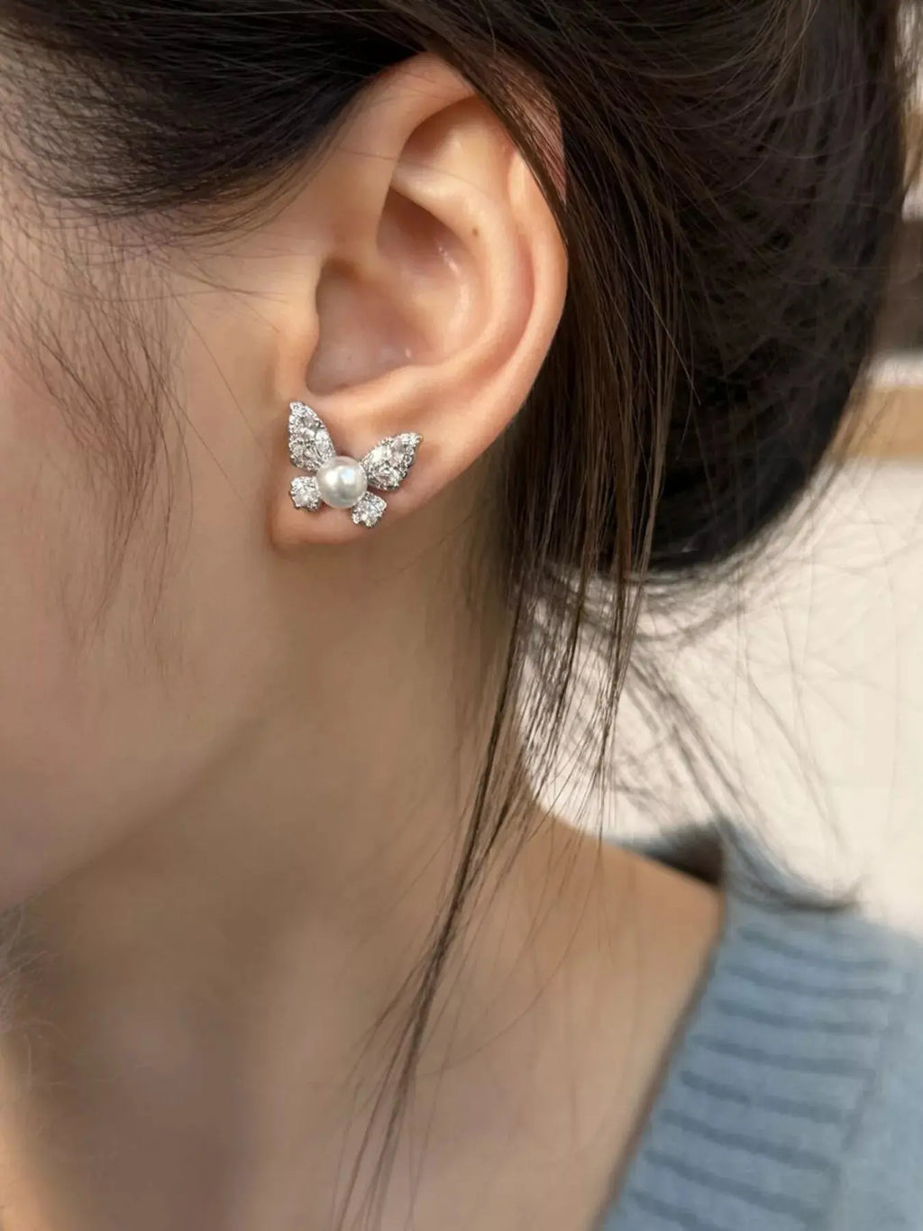 Woman wearing butterfly pearl stud earrings