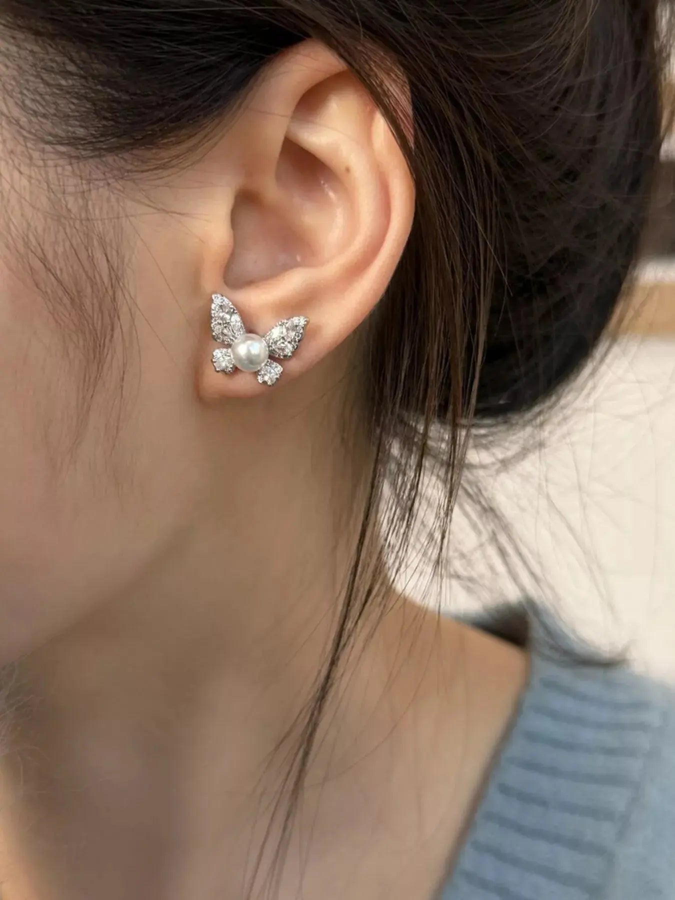 Woman wearing butterfly pearl stud earrings