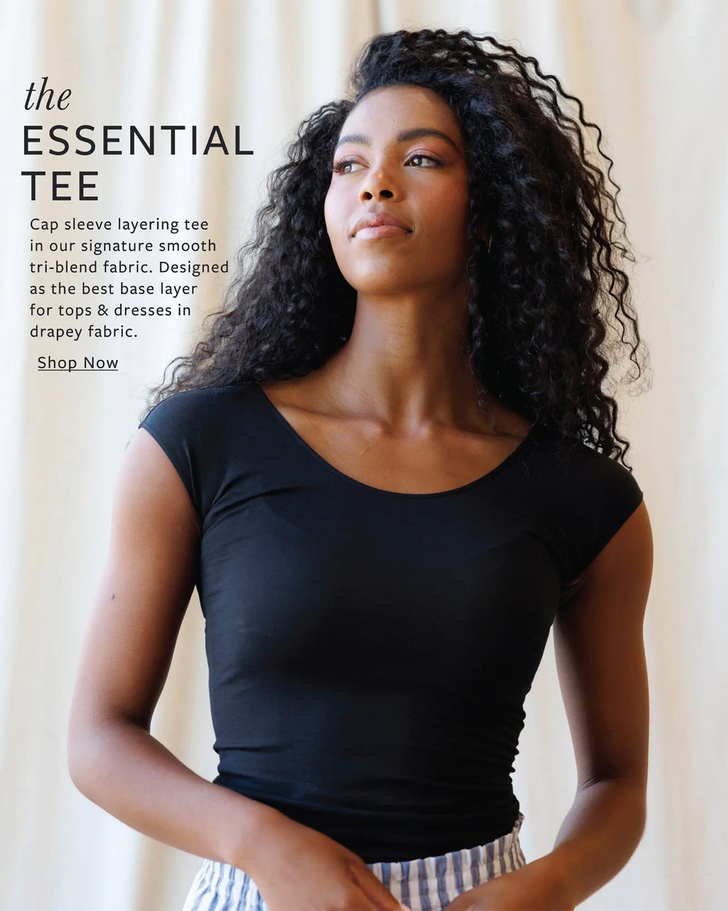 Woman wearing a black cap sleeve layering tee with promotional text on a beige background