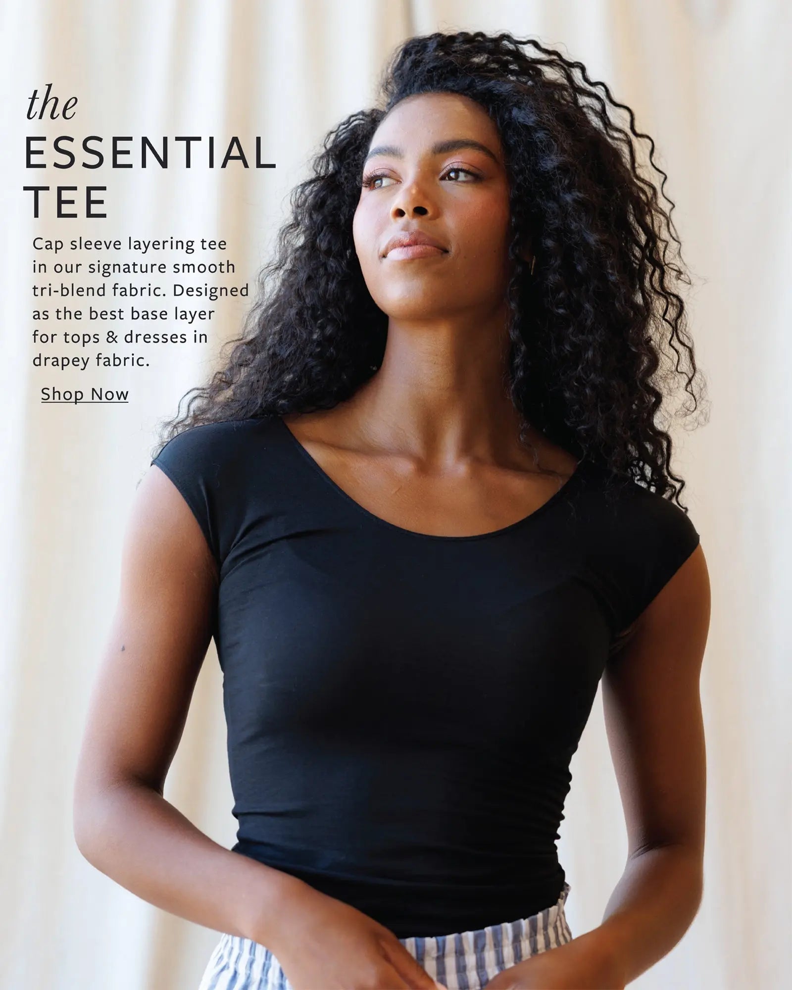 Woman wearing a black cap sleeve layering tee with promotional text on a beige background