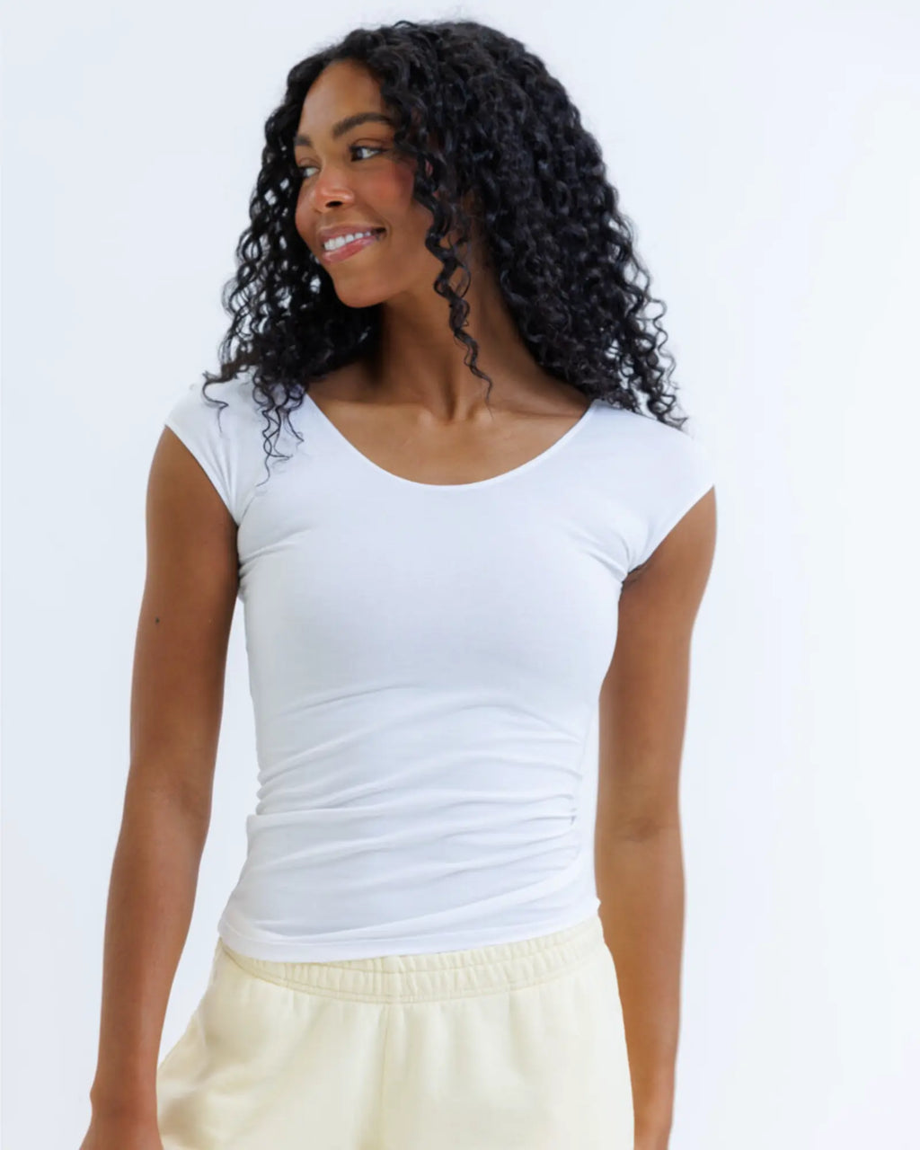 Woman wearing a white sleeveless top against a plain background