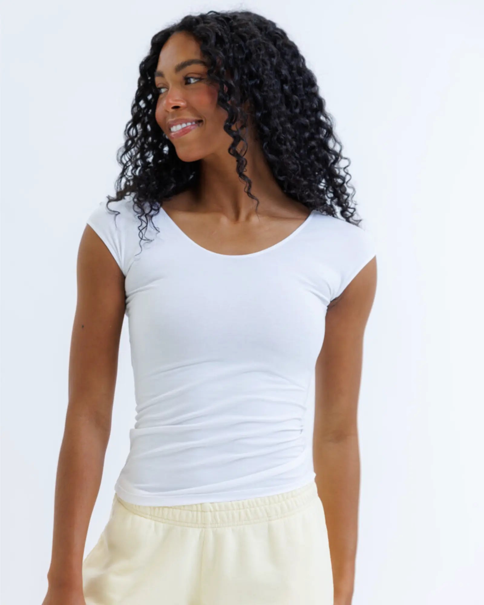 Woman wearing a white sleeveless top against a plain background
