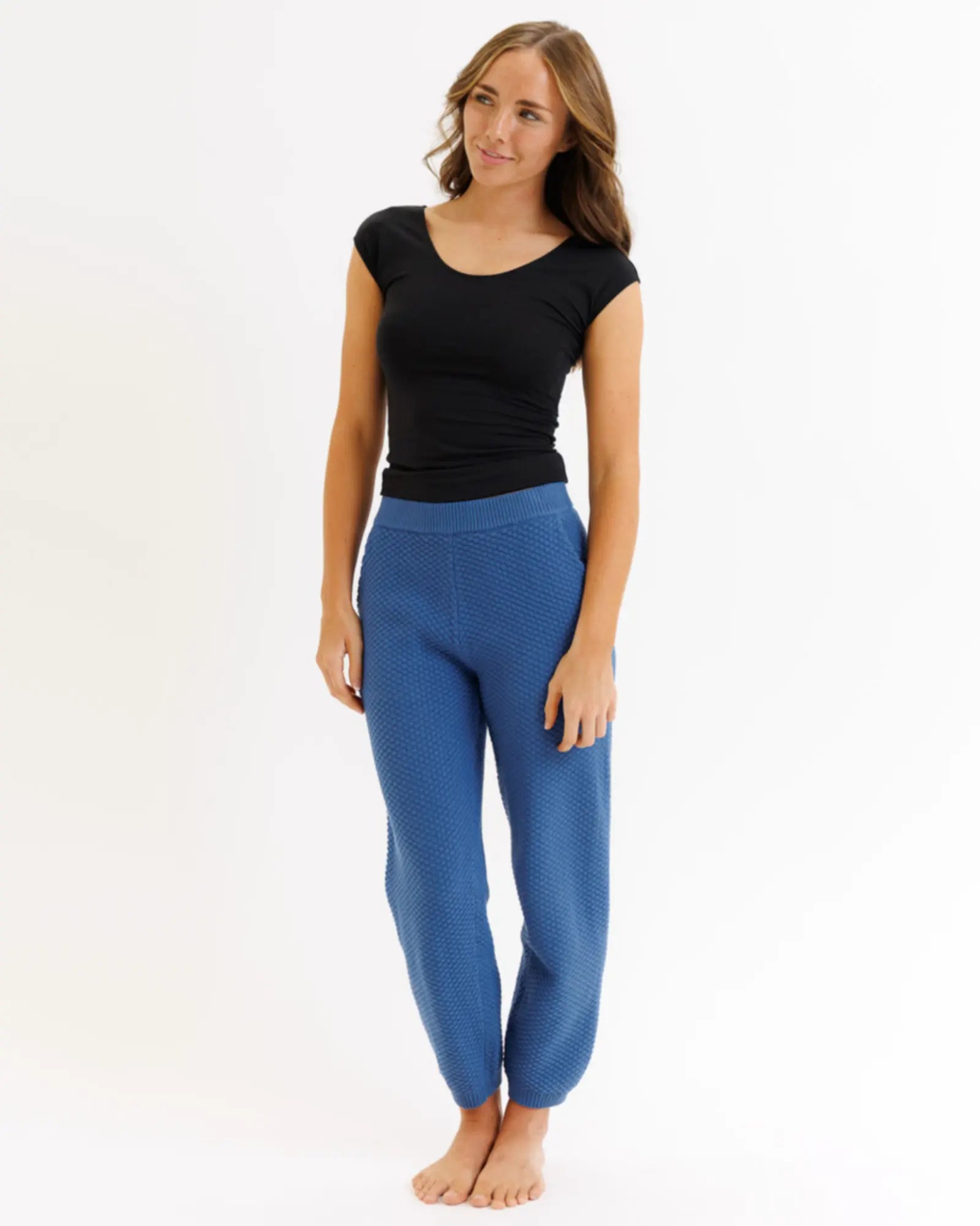 Woman wearing blue pants and a black top on a white background