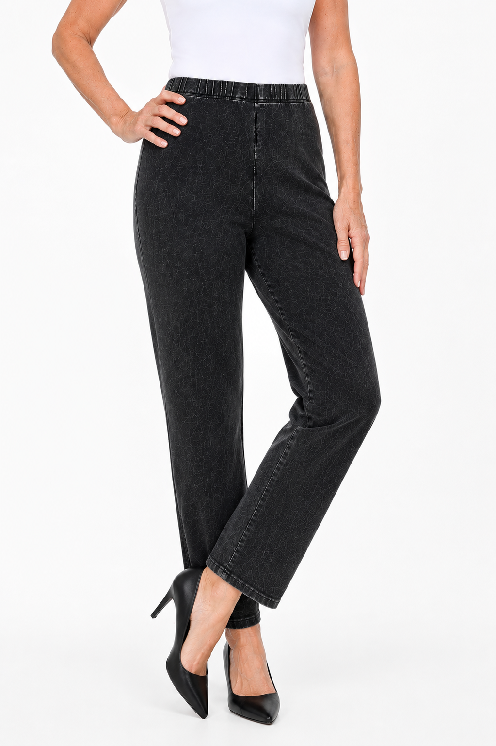A model wearing a pair of black high-waisted, straight-leg cropped jeans with a subtle faded texture, styled with a white top and black heels against a white studio background. Vicsxox.com