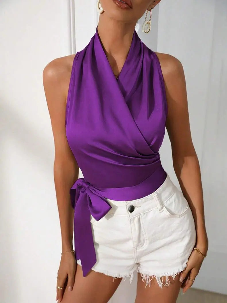 Woman wearing a purple top and white shorts against a plain background
