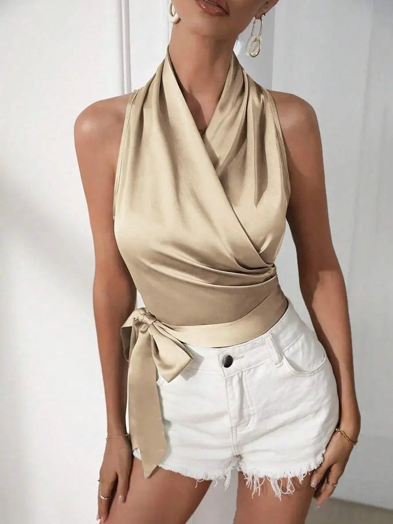 Woman wearing a beige sleeveless top and white shorts against a plain background