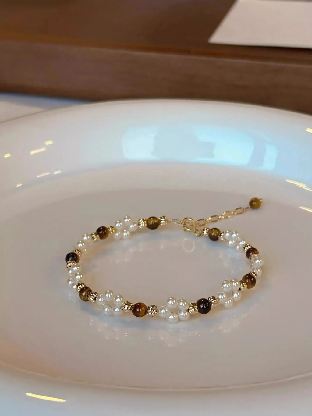 Pearl and brown bead bracelet on a white plate