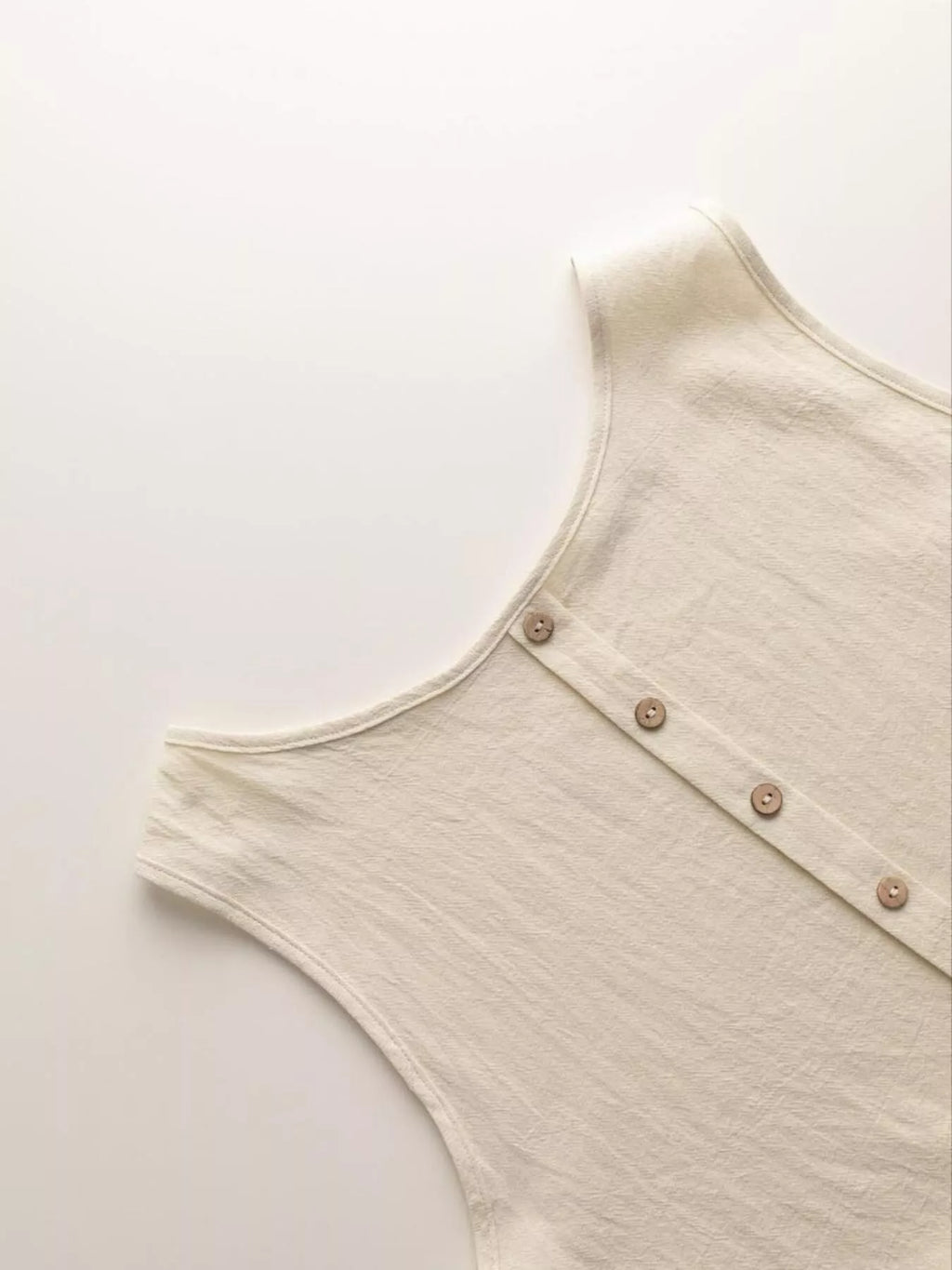 Beige sleeveless top with button details on a light gray background