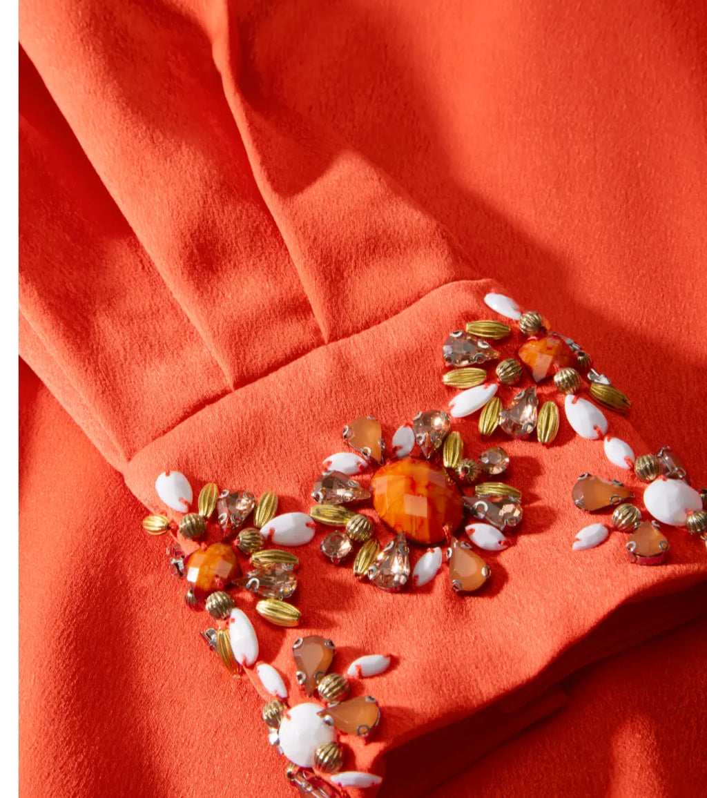 Decorative brooch with multicolored stones on a red fabric background