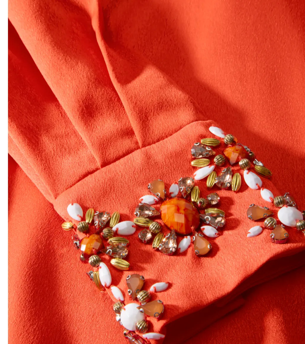 Decorative brooch with multicolored stones on a red fabric background