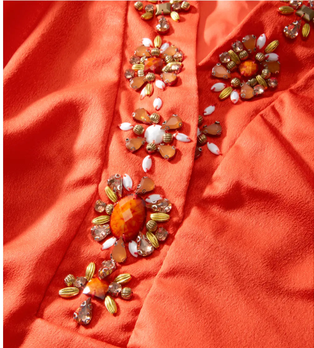Decorative orange fabric with bead embellishments on a red background