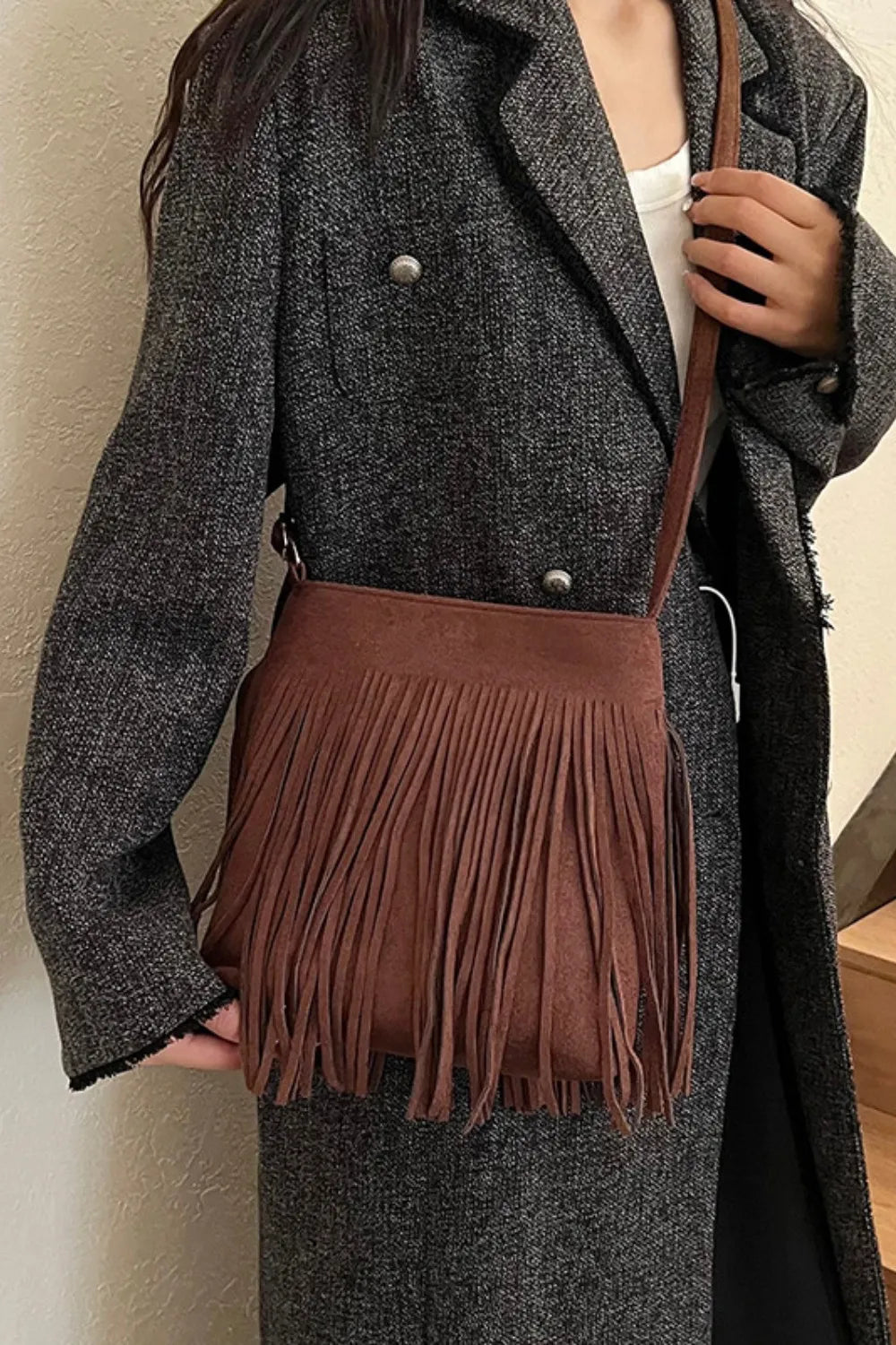 Person wearing a gray coat holding a brown fringed handbag. Vicsxox.com