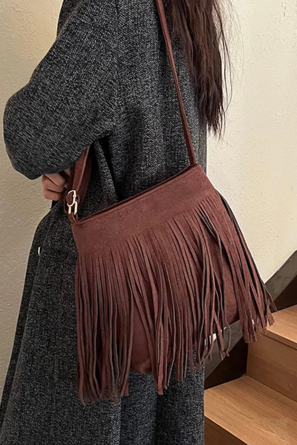 Brown fringed handbag held by a person wearing a gray coat. Vicsxox.com