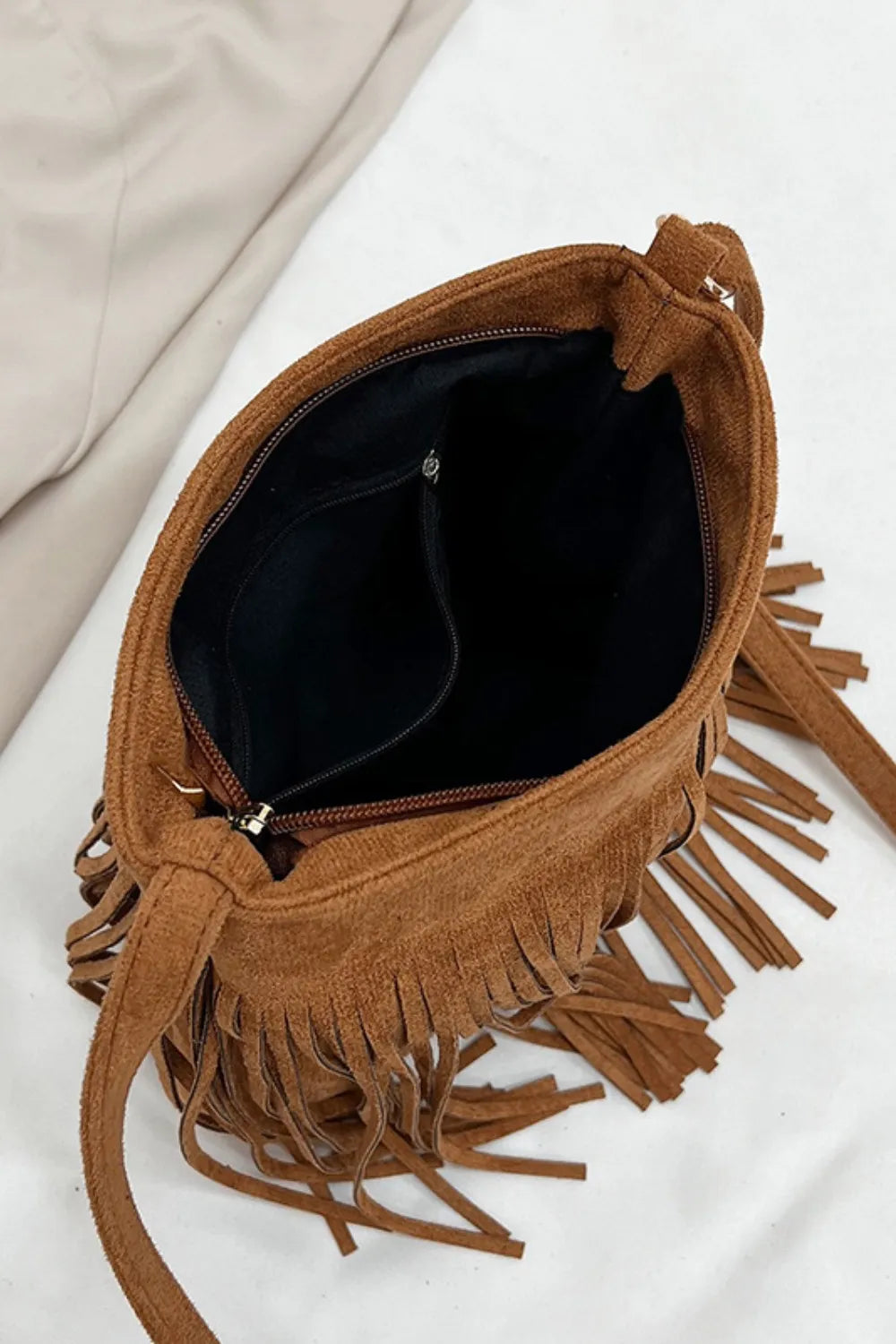 Brown suede handbag with fringe details on a light background. Vicsxox.com