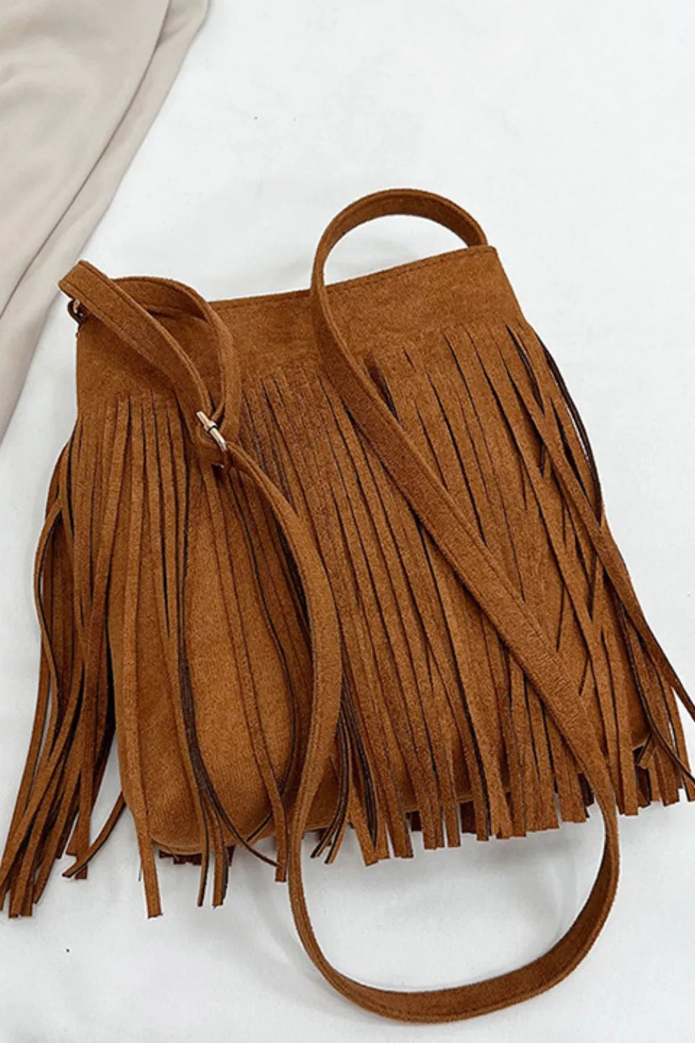 Brown suede handbag with fringe details on a white background. Vicsxox.com