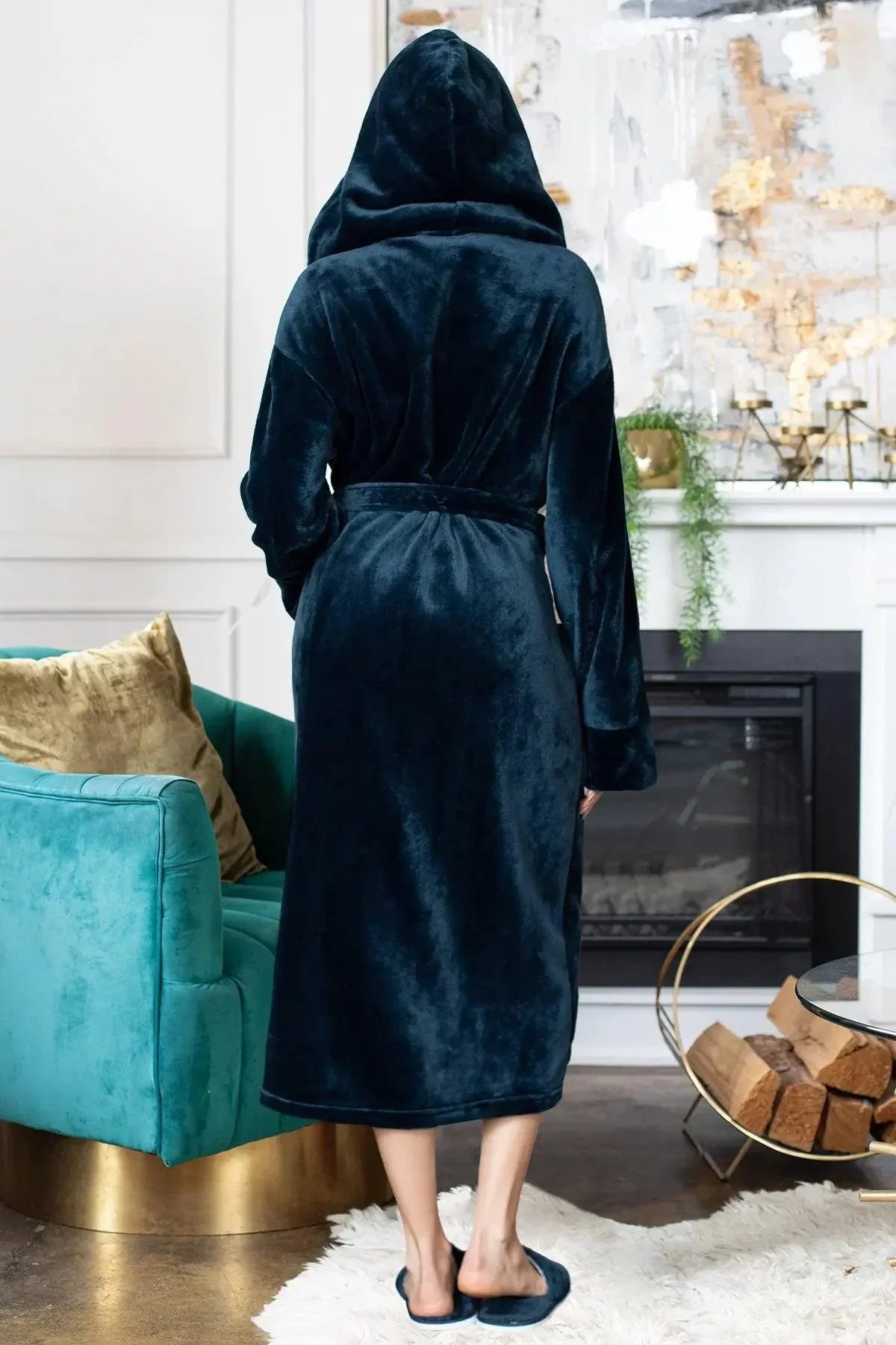 Person wearing a dark blue robe in a cozy living room setting. Vicsxox.com
