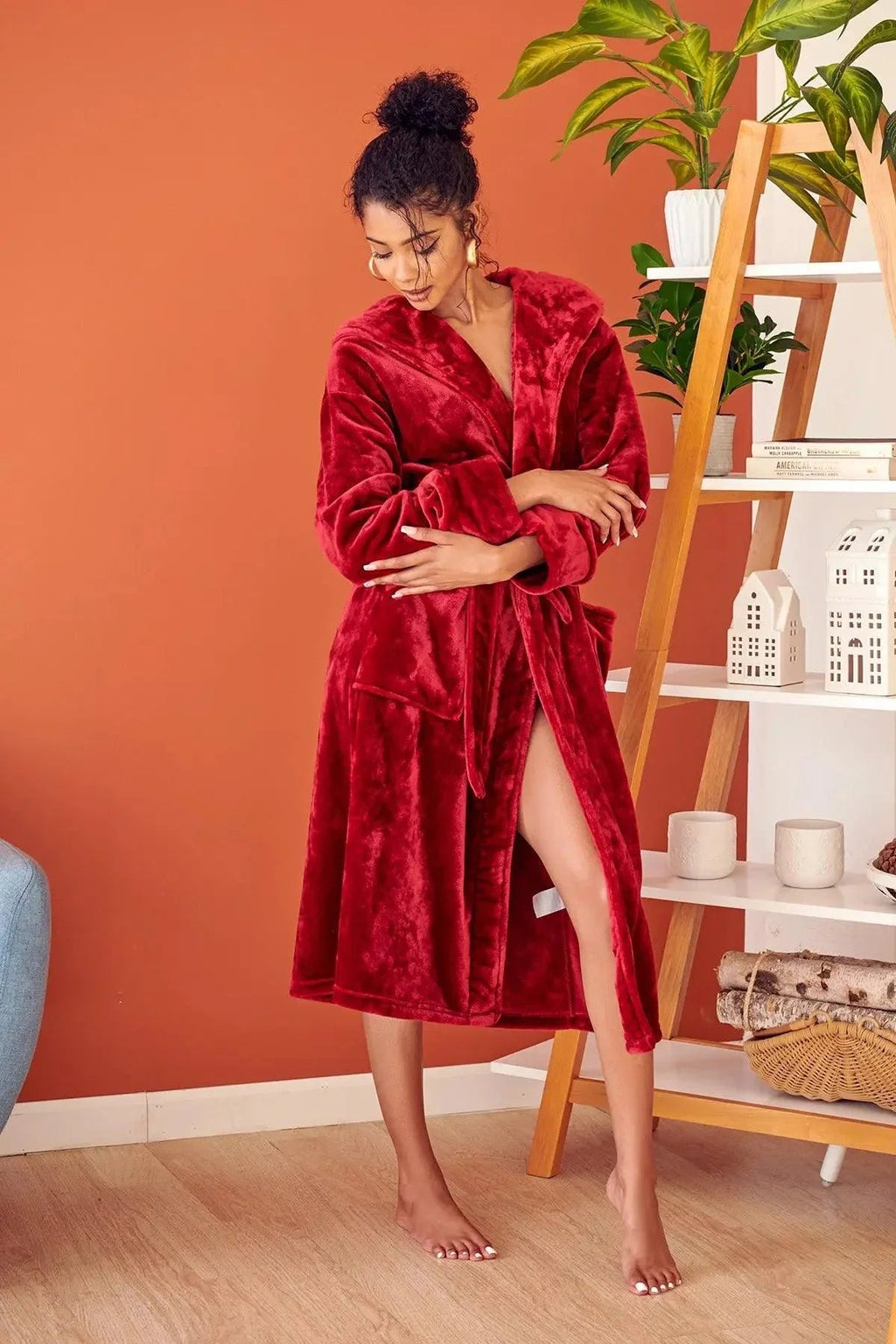 Woman wearing a red robe in a room with an orange wall and a plant. Vicsxox.com