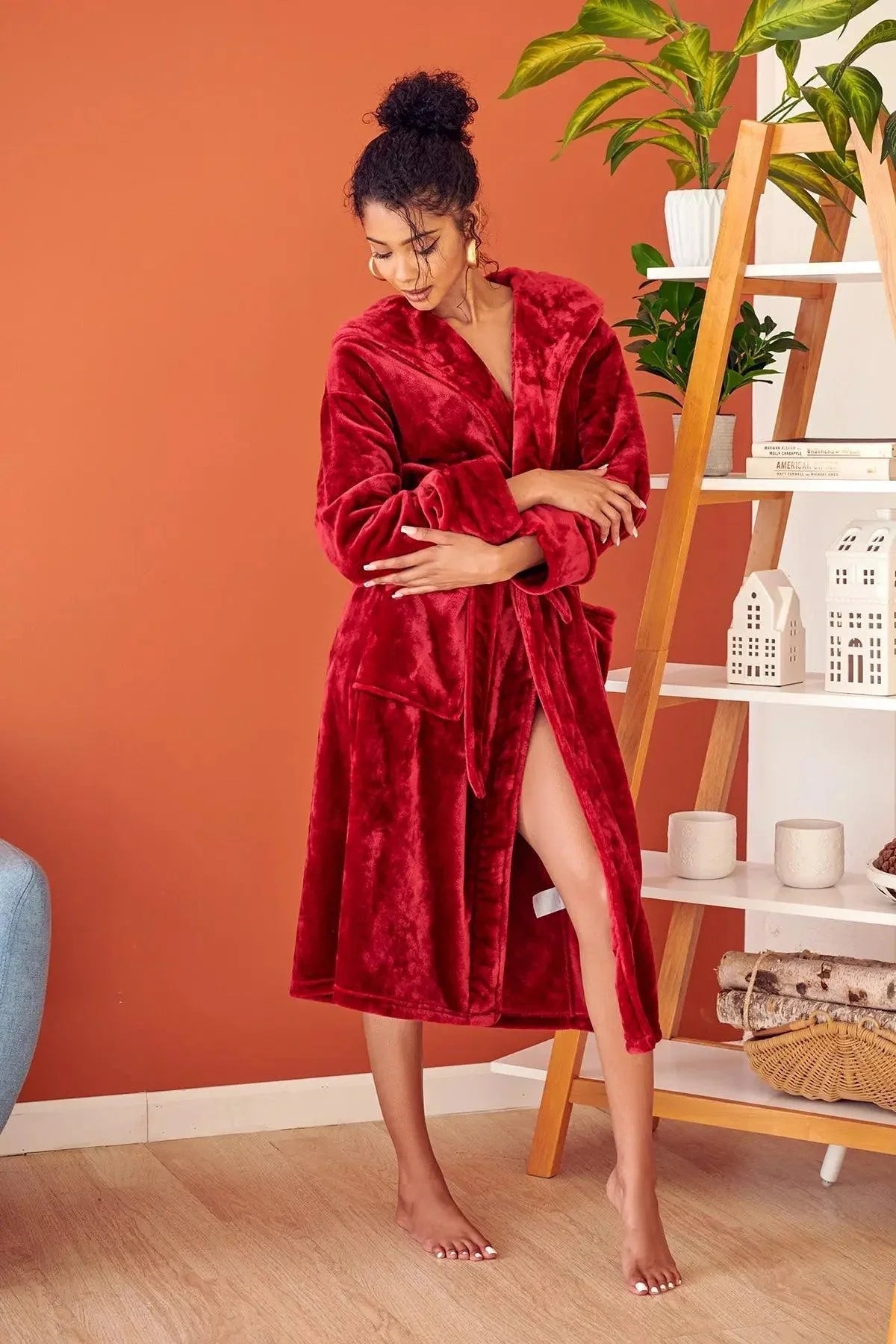 Woman wearing a red robe in a room with an orange wall and a plant. Vicsxox.com