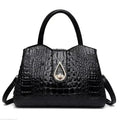 Black crocodile-patterned handbag with a gold teardrop clasp on a white background