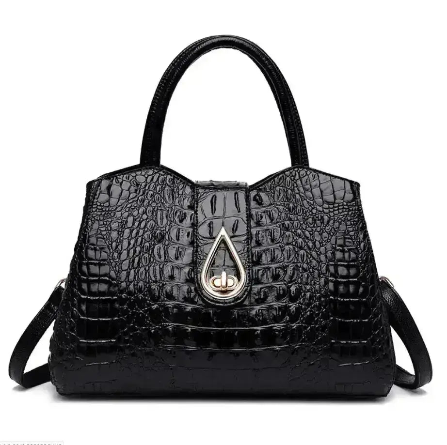 Black crocodile-patterned handbag with a gold teardrop clasp on a white background