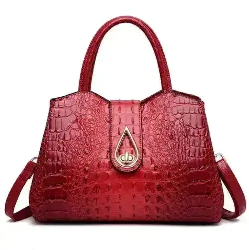Red crocodile-patterned handbag with a gold clasp on a white background