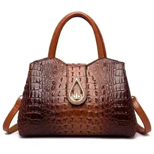 Brown crocodile-patterned handbag with a gold emblem on a white background