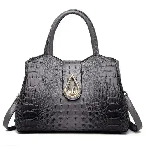 Black crocodile-patterned handbag with a gold clasp on a white background