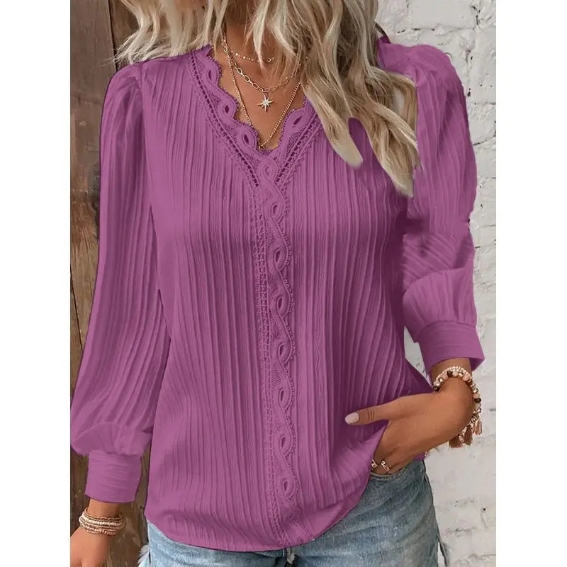 Purple blouse with lace details worn by a person against a white brick wall.