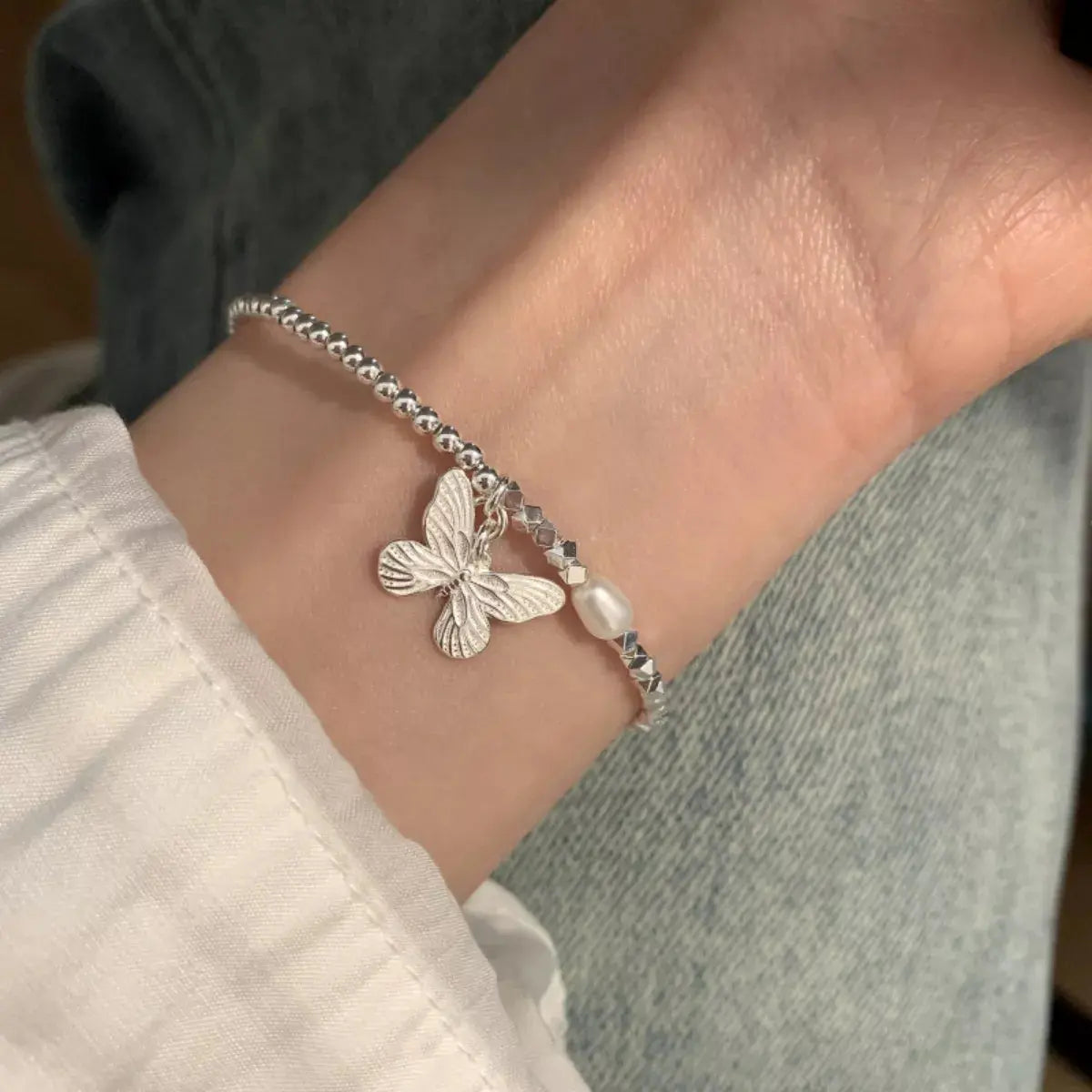 Woman wearing silver butterfly pearl bracelet