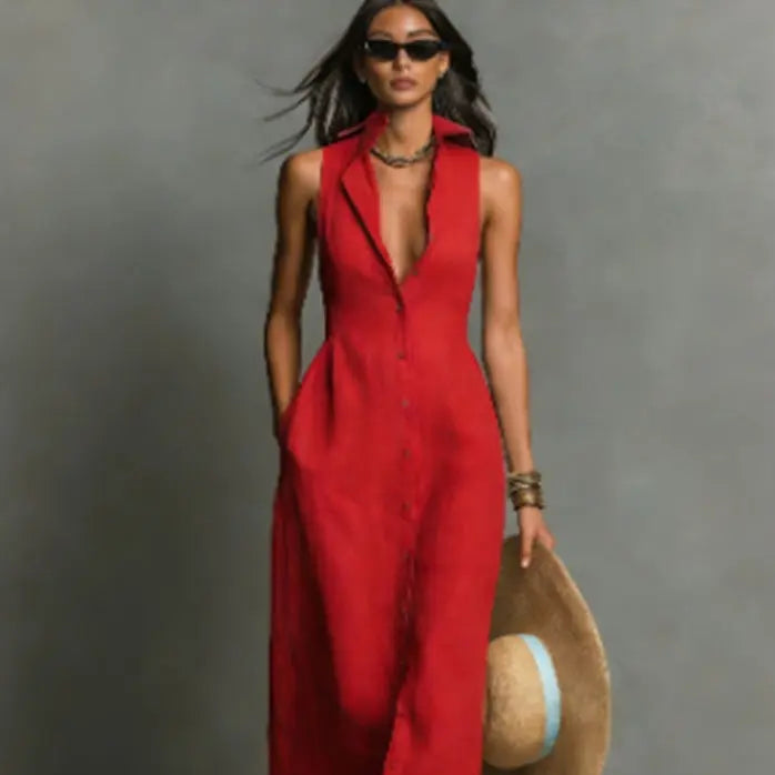 Woman in a red jumpsuit holding a straw hat against a gray background